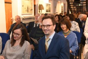 Widownia koncertu. Na pierwszym planie młody mężczyzna i młoda kobieta. Wszyscy elegancko ubrani