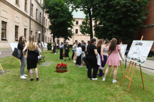 Pomiędzy ustawionymi na trawie sztalugami z projektami, krąży grupa ludzi