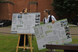 Dwie studentki układają swoje projekty na sztalugach.