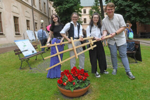 Czworo studentów pozuje do zdjęcia trzymając sztalugę.