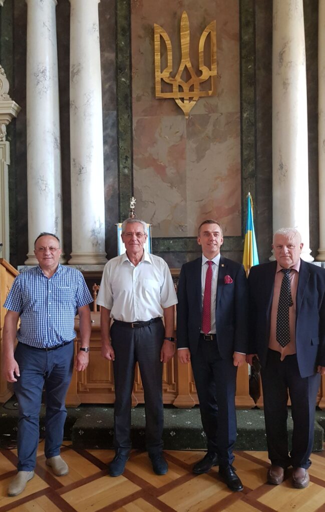 Rektor Politechniki Krakowskiej Andrzej Szarata (drugi z prawej) odwiedza Politechnikę Lwowską. Na zdjęciu czterech mężczyzn na tle ściany ze złotym godłem Ukrainy. Drugi z lewej rektor Politechniki Lwowskiej prof. Jurij Bobalo.