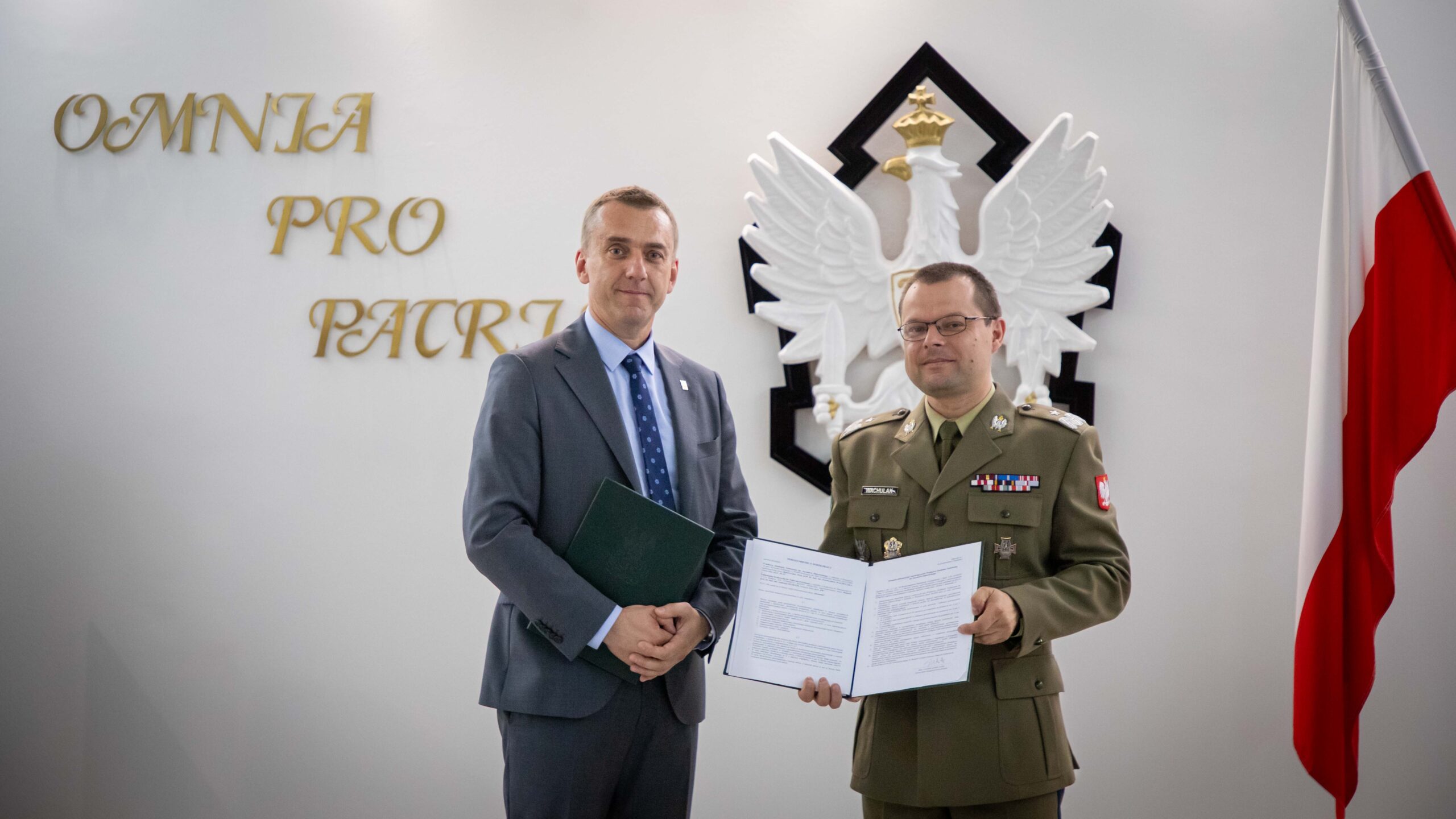 Rektor Politechniki Krakowskiej profesor Andrzej Szarata i Rektor-Komendant WAT generał bryg. profesor Przemysław Wachulak pozują do zdjęcia. Rektor-Komendant trzyma umowę.