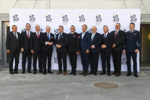 Grupa mężczyzn w garniturach pozuje na tle ścianki z logo Sieci Łukasiewicz