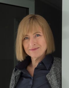 Dziekan Kozień-Woźniak na zdjęciu portretowym, patrzy w obiektyw z lekko przechyloną na bok głową