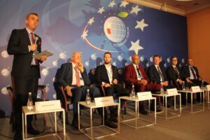 Rektor PK moedruje panel dyskusyjny. Stoi z mikrofonem w ręku. Obok siedzą uczestnicy dyskusji