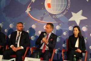 Rektor PK zabiera głos, trzyma w ręce mikrofon. Siedzi w fotelu, a po jego prawej i lewej uczestnicy dyskusji