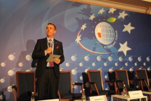 Rektor PK stoi w miejscu obrad, trzyma mikrofon. Krzesła dla gości jeszcze puste. Rektor zaczyna zapraszać uczestników panelu