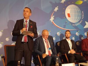 Prof. Andrzej Szarat moderuje panel dyskusyjny. Stoi z mikrofonem i przedstawia gości