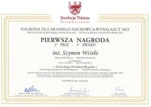 Na górze logo Fundacji Polonia International, potem napis „nagroda dla młodego naukowca-wynalazcy 2023 (również po francusku i angielsku). Większą czcionką: Pierwsza nagroda inż. Szymon Wcisło. Niżej: za projekt „Technologia produkcji biopaliw” przedstawiony podczas XVI międzynarodowych targów wynalazków i innowacji IT=NTARG 2023 Katowice (PL) 25.05.2023. Na dole trzy podpisy. Wokół złota ozdobna ramka