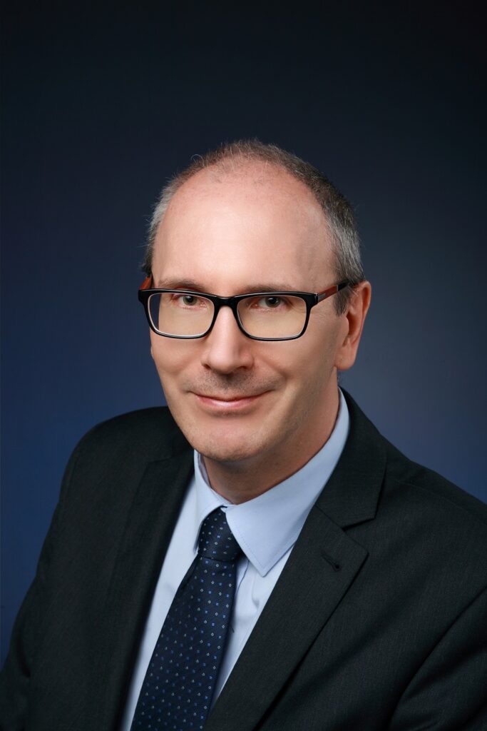 Zdjęcie portretowe Krzysztofa Pielichowskiego. Profesor patrzy w obiektyw, lekko się uśmiecha, okulary 