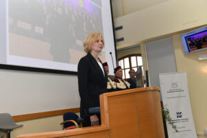 Prof. Małgorzata Cimochowicz-Rybicka stoi na katedrze, za nią prorektorzy i pełnomocnik Vogt