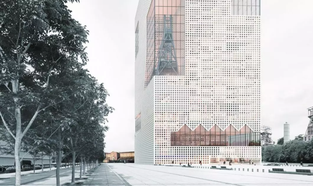 Wysoki budynek z ażurową fasadą, w której widoczne są spore przeszklenia. Projekt M. Krzysteczko