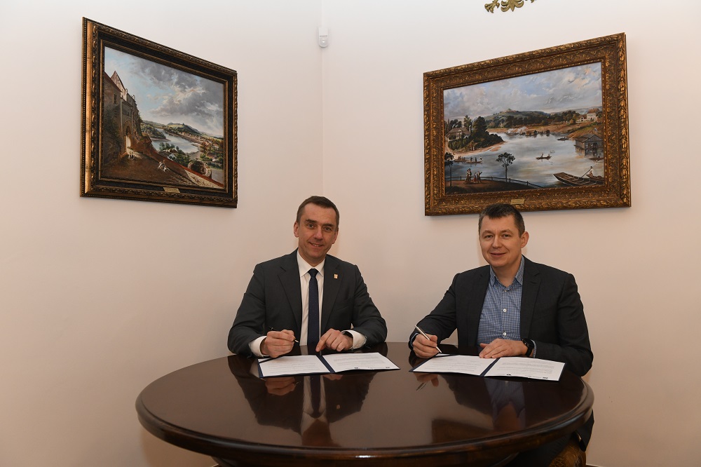 Przy stole siedzą rektor PK prof. Andrzej Szarata i dyrektor MCN „Cogiteon” Piotr Szymański , trzymają w rękach długopisy. Na stole leżą umowy