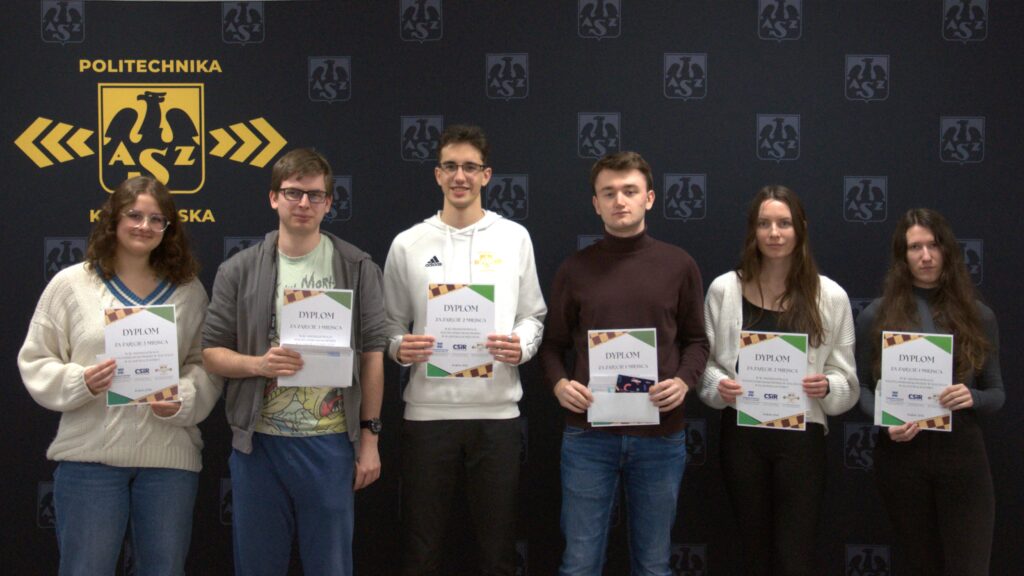 Grupa ludzi pozuje do zdjęcia trzymając w rękach pamiątkowe dyplomy Mistrzostw w Szachach. Za nimi znajduje się ścianka reklamowa z logo AZS. Są to osoby zajmujące miejsca od 1 do 3 w kategorii kobiet i mężczyzn