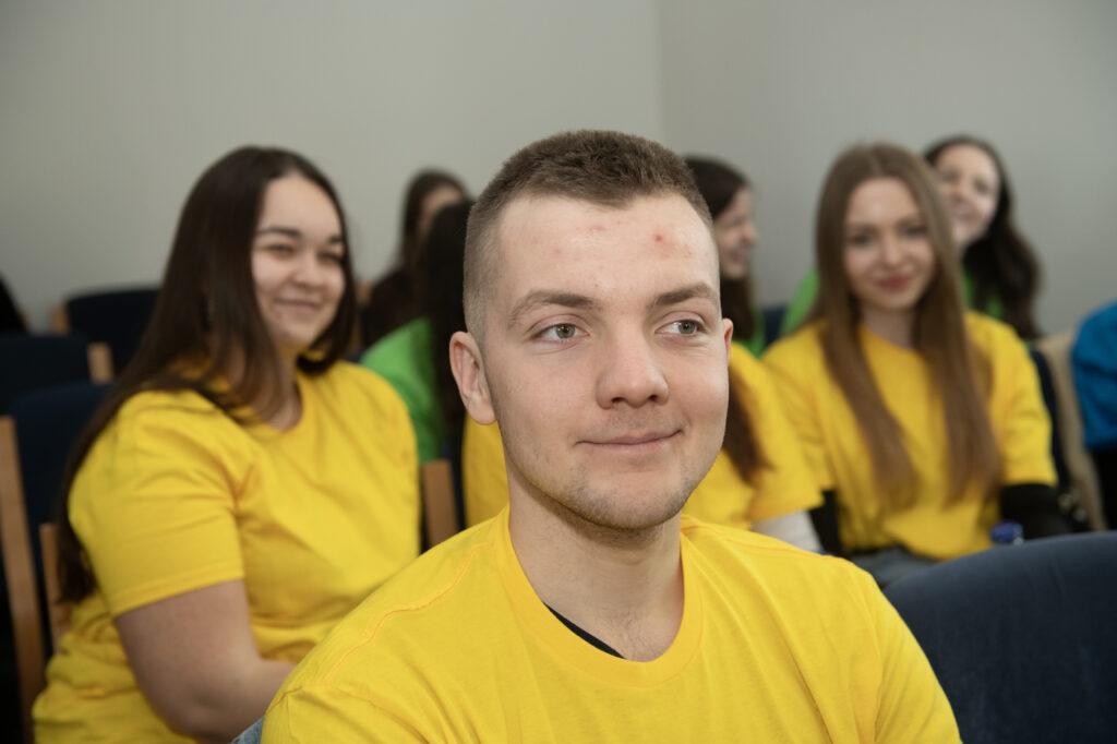 Studentki i studenci PK siedzą na widowni, ubrani są w żółte koszulki