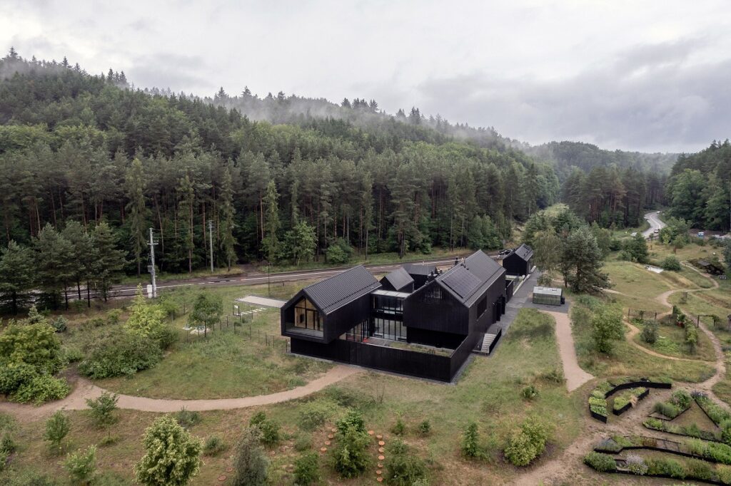 Budynek edukacyjny w Leśnym Ogrodzie Botanicznym Marszewo. Ciemna elewacja wtapiająca się w okolicę porośniętą lasem