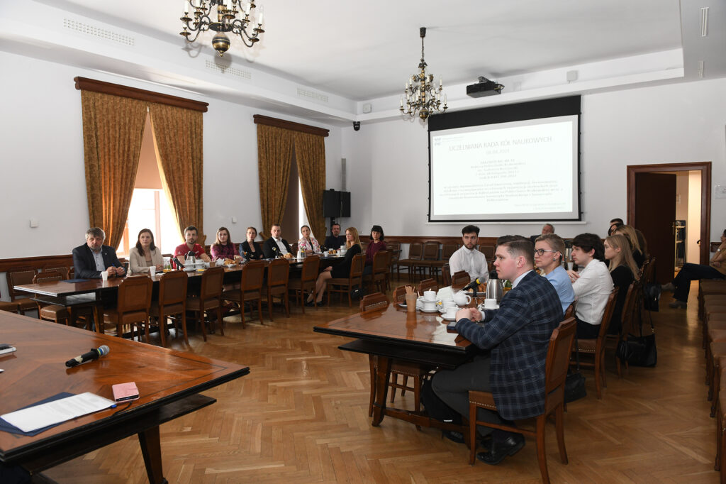 Uczestnicy pierwszego posiedzenia URKN siedzą za stołami w Sali Senackiej