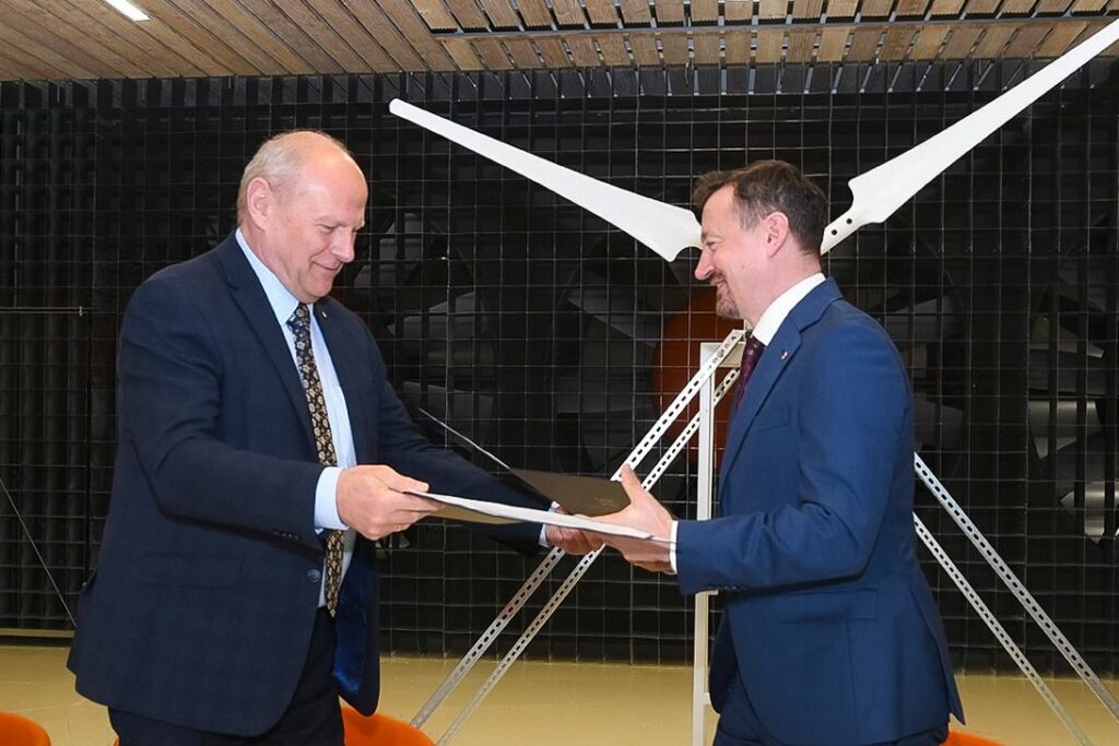 Prorektor Kapecki i Adam Małysz podają sobie egzemplarze umów